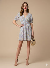 Cargar imagen en el visor de la galería, Vestido Lucía - Este encantador vestido corto, confeccionado en una tela ligera y fluida con una caída impecable, destaca por su delicado estampado floral en tonos lila, azul y ocre sobre un fondo neutro.