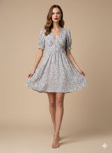 Cargar imagen en el visor de la galería, Vestido Lucía - Este encantador vestido corto, confeccionado en una tela ligera y fluida con una caída impecable, destaca por su delicado estampado floral en tonos lila, azul y ocre sobre un fondo neutro.
