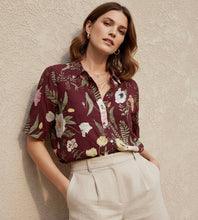 Cargar imagen en el visor de la galería, Delia ✨
Blusa de manga corta con estampado floral sobre fondo vino, cuello camisero y botonadura frontal que crea un look femenino, sofisticado y fácil de llevar del día a la noche.